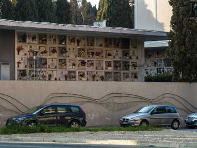 Sulla destra si profila invece il camposanto cittadino, di cui scorgiamo alcuni loculi nascosti tra gli alti cipressi